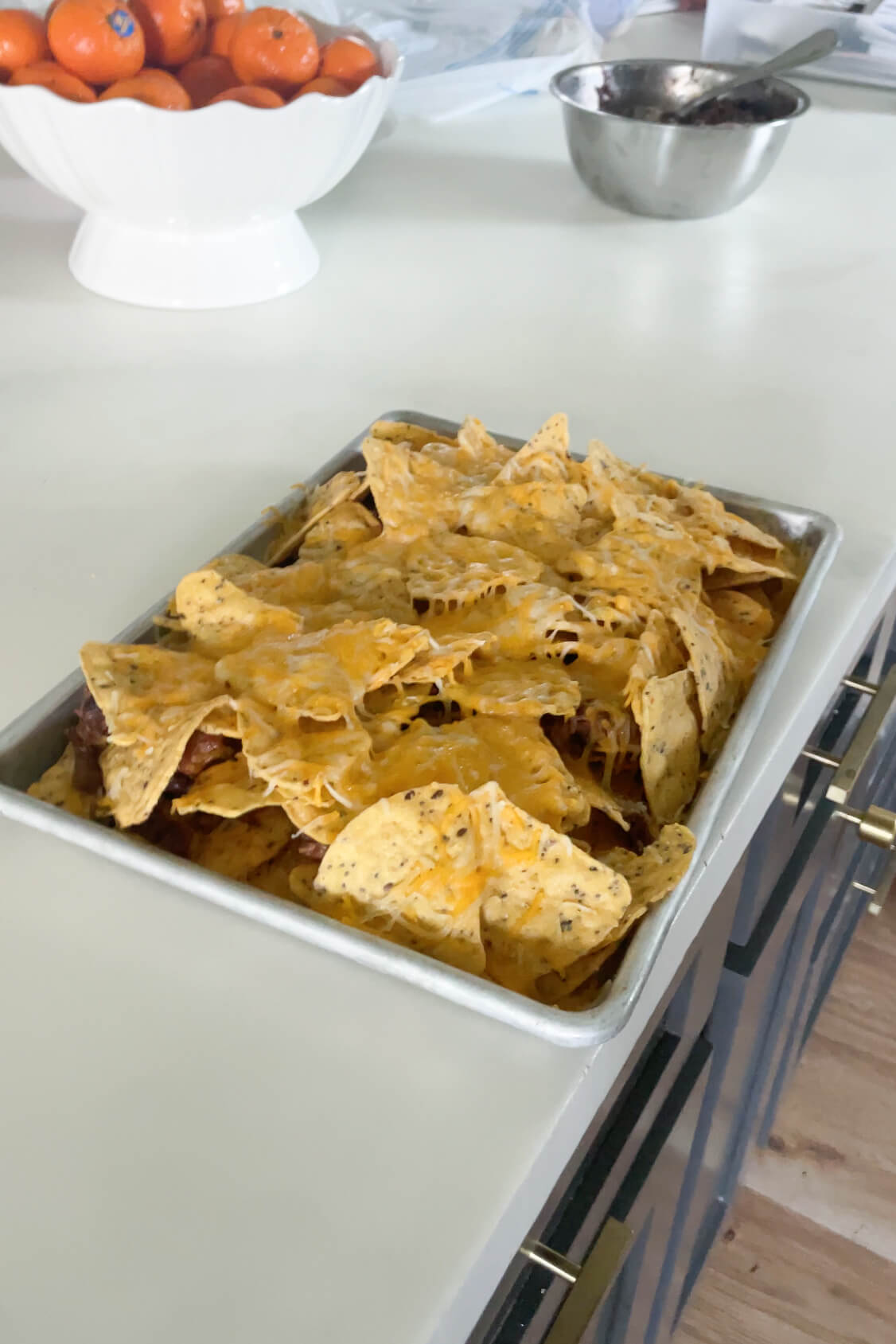 Melting cheese by putting the sheet pan nachos in the oven. 